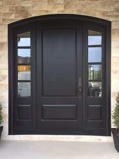 a black front door with two potted plants