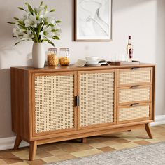 a sideboard with wicker doors and drawers in a room next to a potted plant