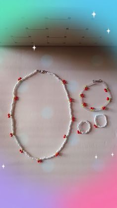 a white beaded necklace and matching bracelet with red beads on a pink, green, blue, and purple background