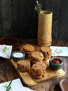 some food is sitting on a cutting board next to a vase with flowers in it