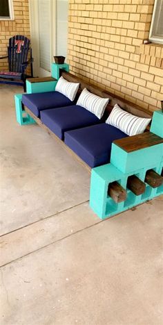 a blue couch sitting on top of a wooden bench next to a brick wall and door