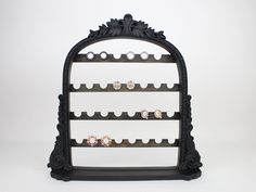 a black display case with several pairs of earrings on it's sides and an ornate design