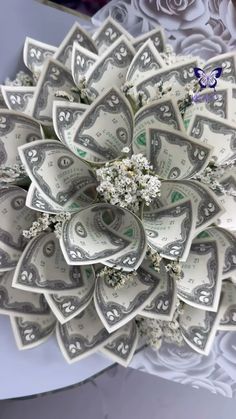 a bunch of money sitting on top of a white table cloth with flowers in the center