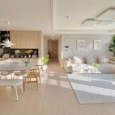 a living room filled with furniture next to a kitchen and dining room table on top of a hard wood floor