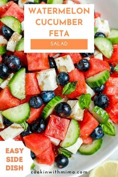 watermelon cucumber feta salad in a white bowl with lemon wedges