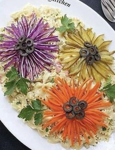 an assortment of colorful flowers on a white plate with silverware and utensils