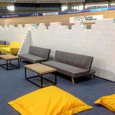 several benches are lined up next to each other in an empty room with yellow pillows