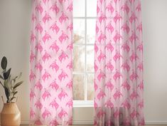 a pink horse print curtain hanging in front of a window with a potted plant next to it