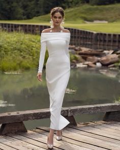 a woman in a white dress standing on a bridge