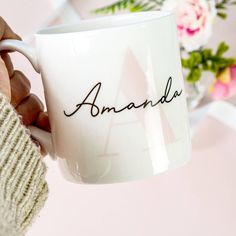 a person holding a coffee mug with the word amanda written on it in cursive writing