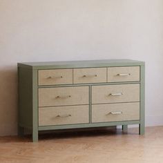 a green dresser sitting on top of a hard wood floor next to a white wall