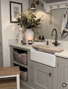 a kitchen sink sitting under a window next to a counter top with flowers in it