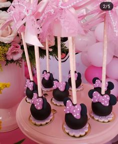 minnie mouse cupcakes with pink bows are on a cake stand in front of balloons