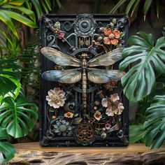 a dragonfly sculpture sitting on top of a wooden table next to plants and flowers