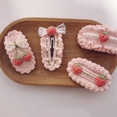 four crocheted hair clips are on a wooden platter with strawberries and bows