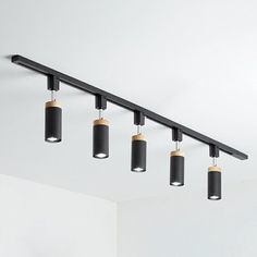 four black and gold lights hanging from the ceiling in an empty room with white walls