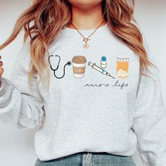 a woman wearing a grey sweatshirt with coffee and nurse's stethoscope on it