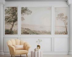 a chair and table in front of three wall paintings with trees on the opposite side