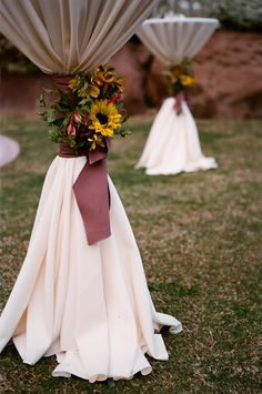 some white cloths with flowers on them are sitting in the grass near an umbrella