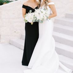 two women in black and white dresses are standing on the steps with their bouquets