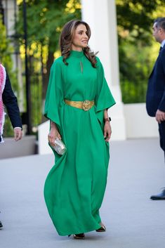 a woman in a green dress is walking down the street with her hand on her hip