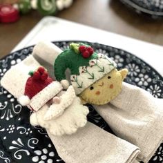 two small knitted christmas hats on top of each other, sitting on a black and white plate