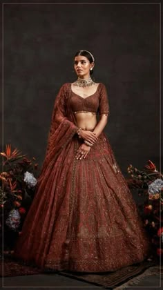 a woman in a red and gold lehenga is standing with her hands on her hips