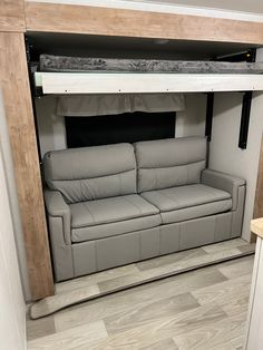 a couch in the corner of a living room under a loft bed that is attached to a wall