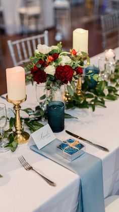 the table is set with silverware, candles, and flowers in glass vases