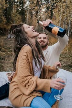 a man and woman sitting on the ground drinking from wine bottles, with an instagramr