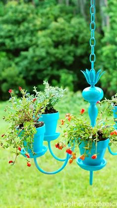 a blue chandelier with potted plants hanging from it's sides in a yard