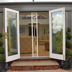 an open patio door leading to a living room with couches and potted plants