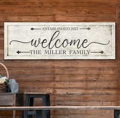 a welcome sign hanging on the side of a wooden wall in front of a table