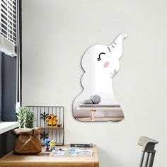 an elephant shaped mirror hanging on the side of a wall next to a chair and table