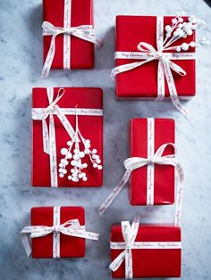 red wrapped presents with white ribbons and bows on a marble table top, ready for someone to put them in