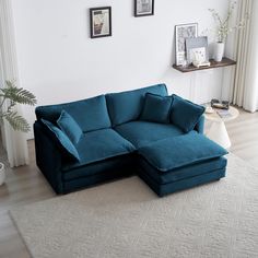 a living room with a large blue couch and white rugs on the floor next to a window