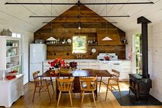 an open kitchen and dining area with wood flooring, white walls, and ceiling beams