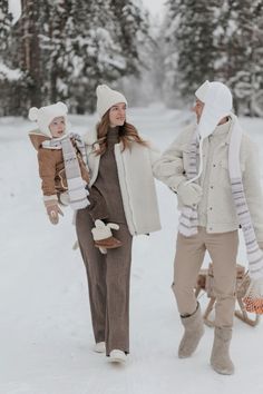 two women walking in the snow with one holding a baby and another carrying an infant