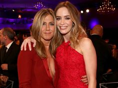 two women in red dresses posing for the camera at an awards event with their arms around each other