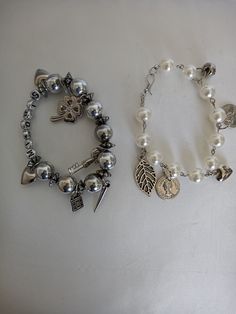 two bracelets with charms on them sitting next to each other