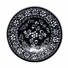 a black and white plate with an intricate design on the front, sitting against a white background