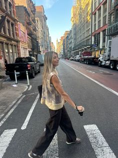 a woman walking across the street with her hand in her pocket while crossing the street