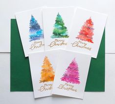 four christmas cards with watercolor trees on them