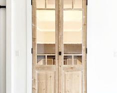 an old wooden cabinet with glass doors in a room that is white and has wood floors