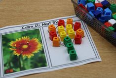 a close up of a magazine on a table with legos and flowers in the background