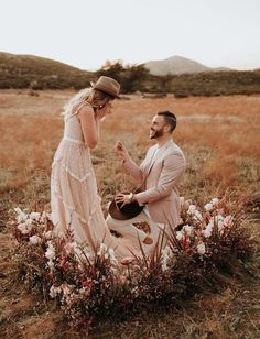 a man kneeling down next to a woman in a field