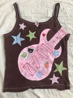 a brown tank top with pink guitar and stars on it