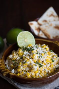 a bowl filled with corn and cheese next to tortilla chips