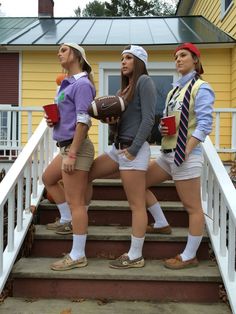 three women dressed up in costumes standing on the steps to a yellow house with white railings