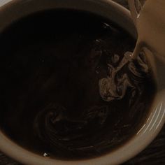 a white bowl filled with liquid on top of a wooden table